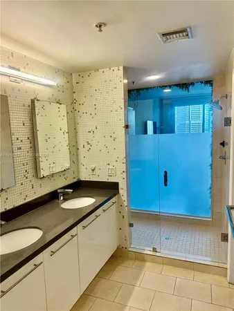 a bathroom with a granite countertop sink a mirror and a shower
