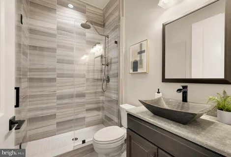 a bathroom with a granite countertop bathtub shower sink vanity and toilet