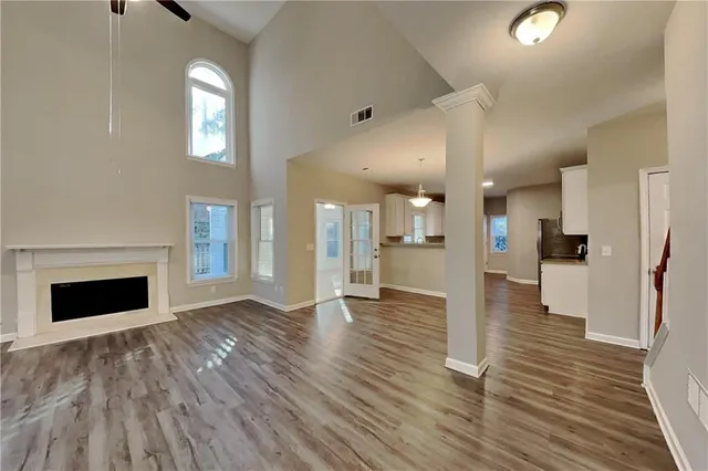a view of a livingroom with wooden floor and a kitchen