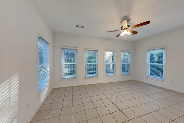 a view of an empty room with a window and chandelier fan