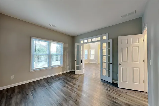 an empty room with wooden floor and windows