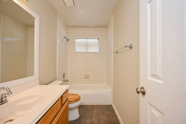 a bathroom with a granite countertop bathtub shower sink vanity and a toilet