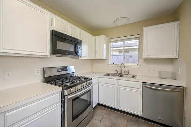 a kitchen with white cabinets appliances and a sink