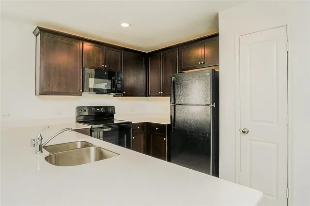 a kitchen with granite countertop a refrigerator stove and sink