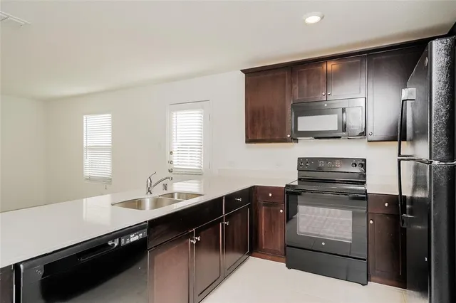 a kitchen with a sink stainless steel appliances cabinets and a window
