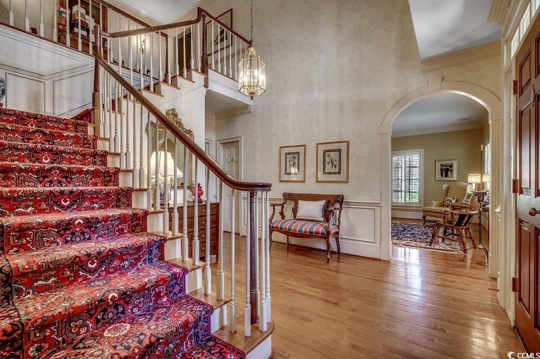 12 Chapin Circle Myrtle Beach, SC 29572 - Photo 12 of 39 Staircase with wood finished floors, arched walkways, a towering ceiling, wainscoting, and crown molding