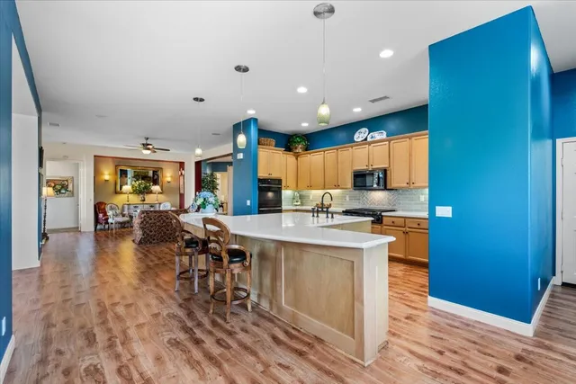 a kitchen with stainless steel appliances a dining table chairs microwave and sink