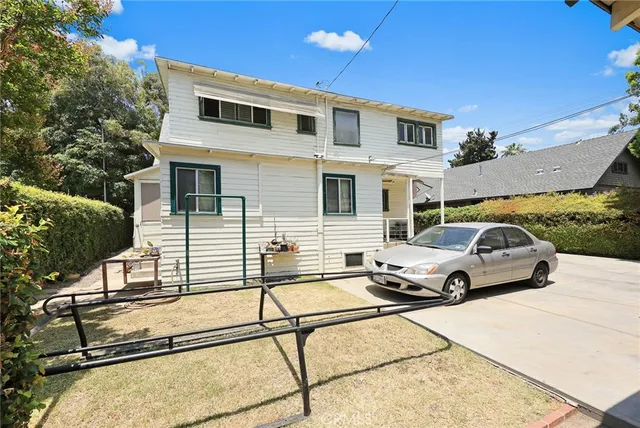 a view of a white house and a yard with potted plants
