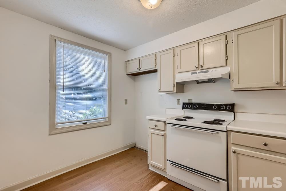 7702 Ohmann Court Raleigh, NC 27615 - Photo 11 of 28 a kitchen with stainless steel appliances granite countertop white cabinets and wooden floor