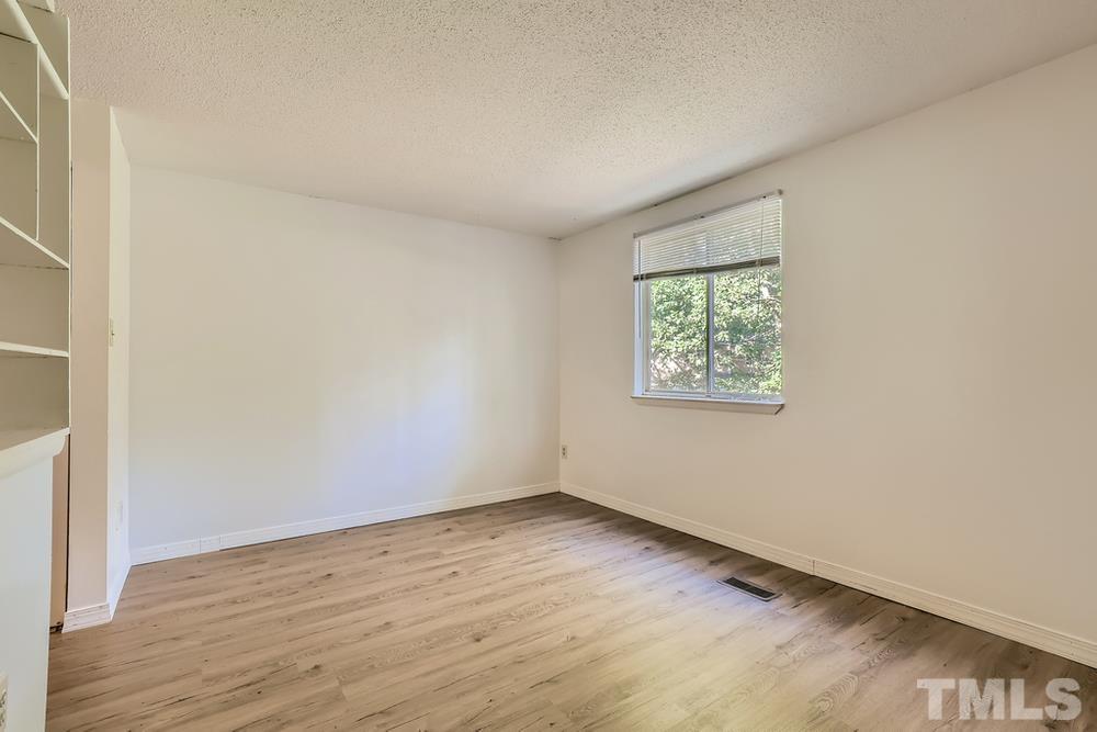 7702 Ohmann Court Raleigh, NC 27615 - Photo 15 of 28 an empty room with wooden floor and windows