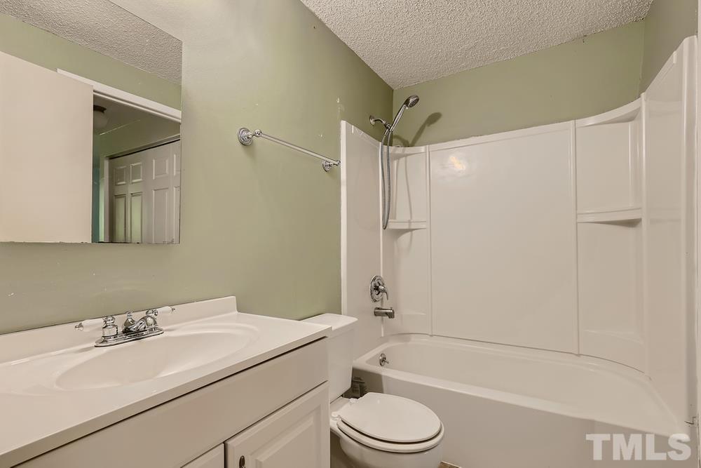 7702 Ohmann Court Raleigh, NC 27615 - Photo 18 of 28 a bathroom with a granite countertop sink toilet and shower