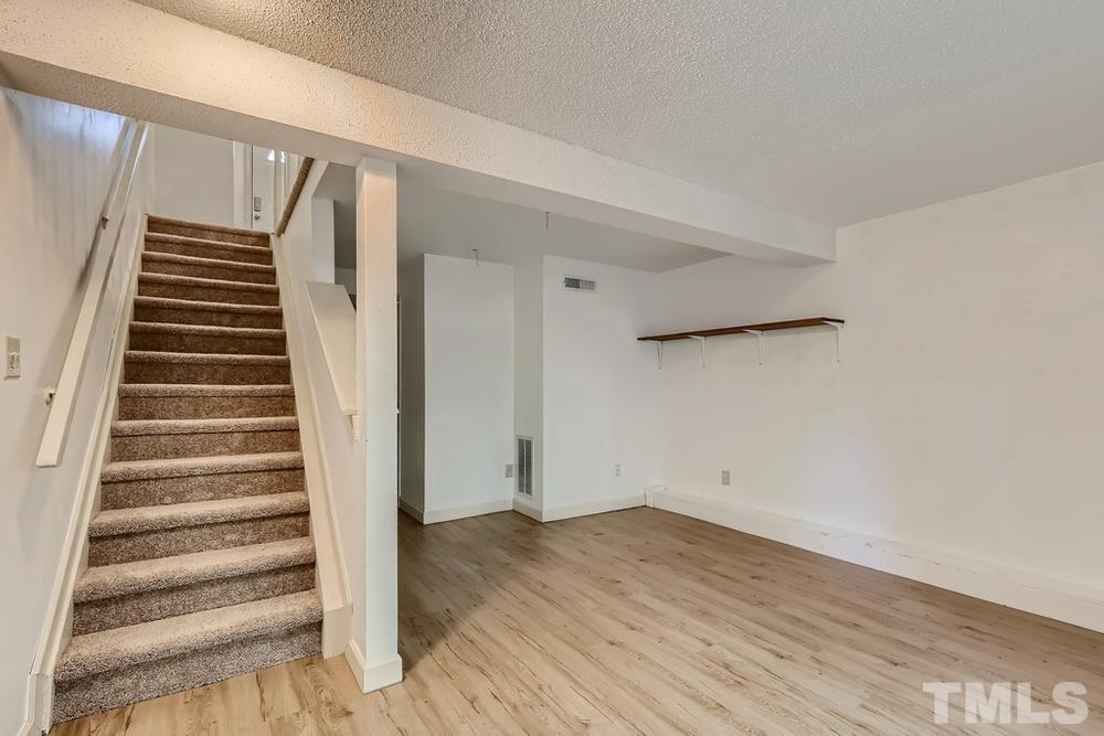 7702 Ohmann Court Raleigh, NC 27615 - Photo 22 of 28 a view of entryway with wooden floor and stairs