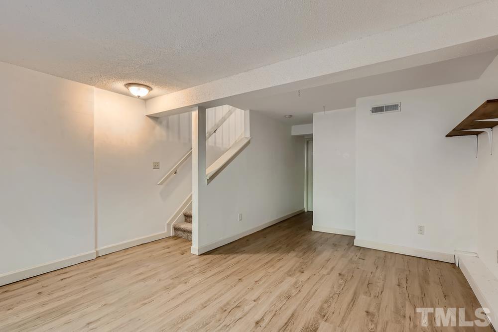 7702 Ohmann Court Raleigh, NC 27615 - Photo 24 of 28 an empty room with wooden floor and windows