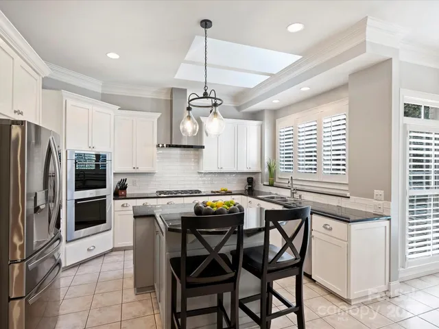 a kitchen with stainless steel appliances granite countertop a sink a stove a refrigerator with a dining table and chairs