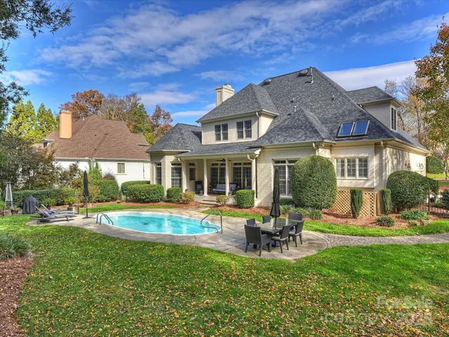 a view of a house with backyard sitting area and swimming pool