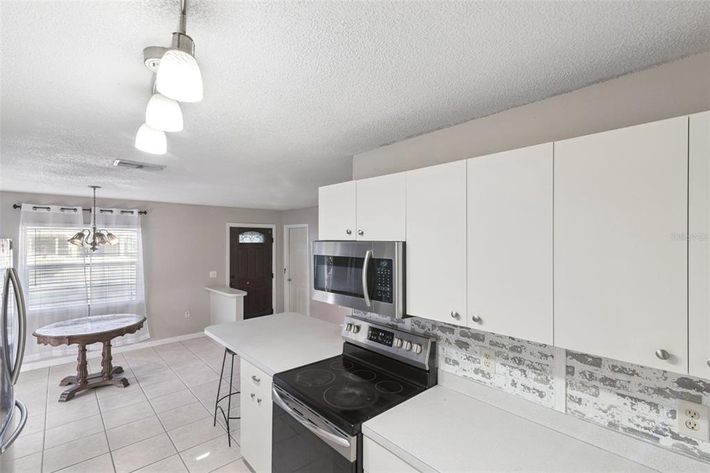 21 Cayman Circle Umatilla, FL 32784 - Photo 6 of 21 a kitchen with kitchen island granite countertop a sink a stove and a microwave