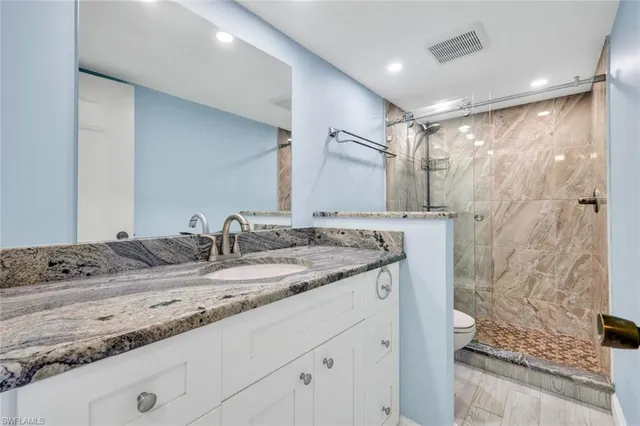 a bathroom with a granite countertop sink a mirror and shower