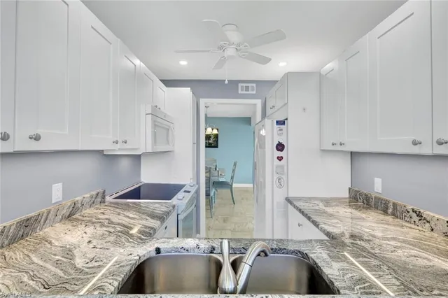 a kitchen with granite countertop a sink and white cabinets