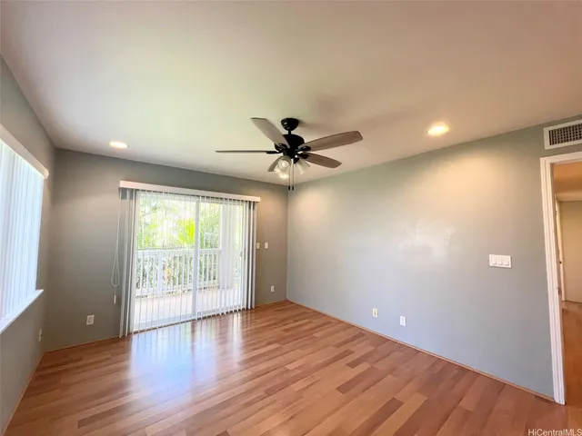 an empty room with wooden floor fan and windows