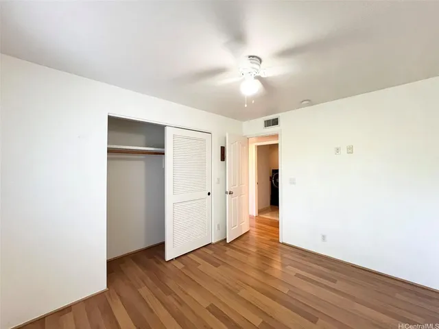 an empty room with wooden floor and ceiling fan