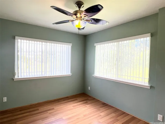a view of an empty room with window and chandelier fan