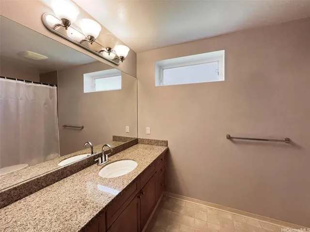 a bathroom with a granite countertop sink a light fixture and a mirror