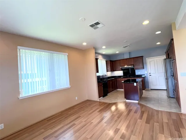 a kitchen with stainless steel appliances kitchen island granite countertop a refrigerator a sink dishwasher a stove and a countertops with wooden floor