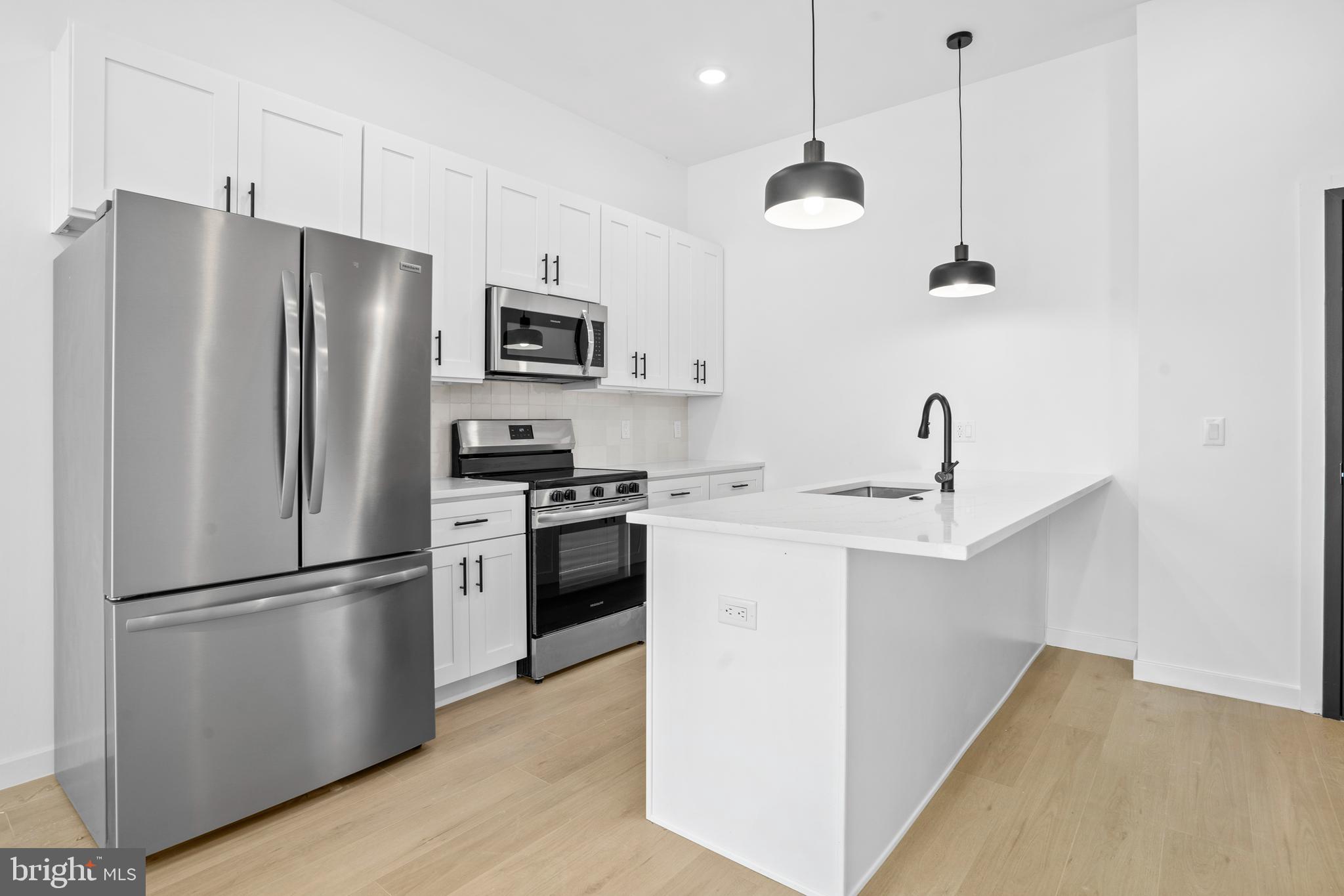 3211 Cedar Street, Unit 306 Philadelphia, PA 19134 - Photo 4 of 18 a kitchen with a refrigerator a sink and cabinets
