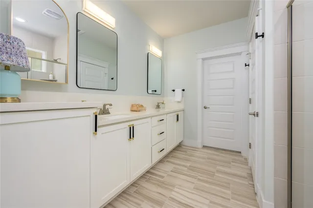 a spacious bathroom with a double vanity sink a mirror and a shower