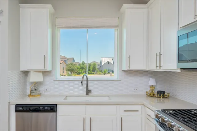 a kitchen with stainless steel appliances granite countertop a sink and a white cabinets
