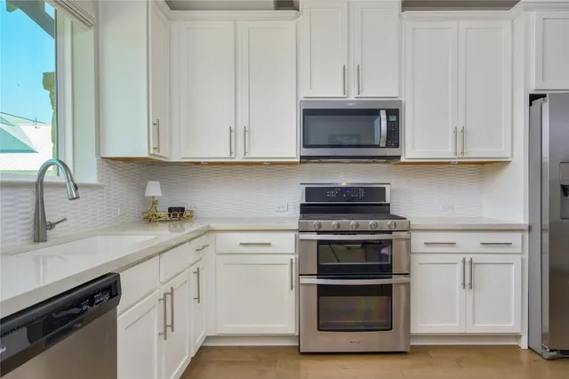 a kitchen with granite countertop white cabinets and stainless steel appliances