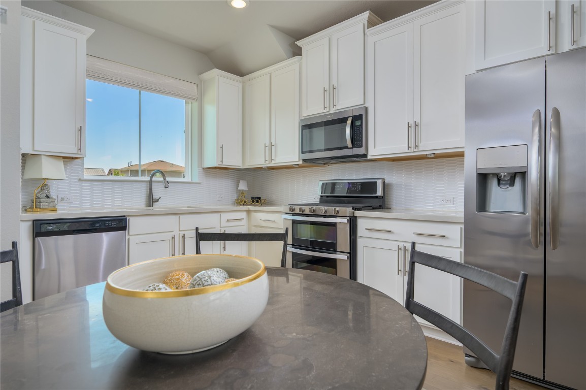 142 Volterra Lane Dripping Springs, TX 78620 - Photo 9 of 37 a kitchen with stainless steel appliances granite countertop a stove a sink dishwasher and a refrigerator with white cabinets