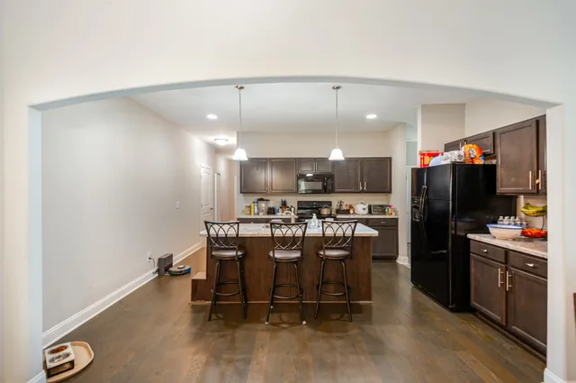 a kitchen with a stove a refrigerator and a dining table with wooden floor