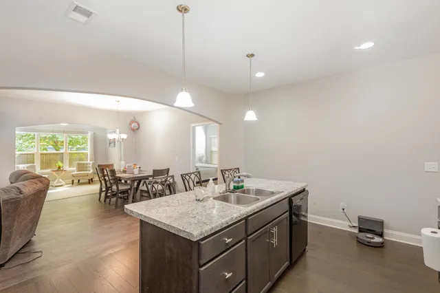 a kitchen with stainless steel appliances granite countertop a table chairs refrigerator and microwave
