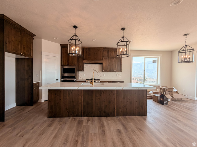 619 East Mountain Road North Ogden, UT 84414 - Photo 3 of 8 Spacious kitchen featuring dark wood cabinetry, a large center island with a light-toned countertop, and modern pendant lighting