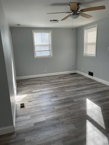 a view of an empty room with wooden floor and window