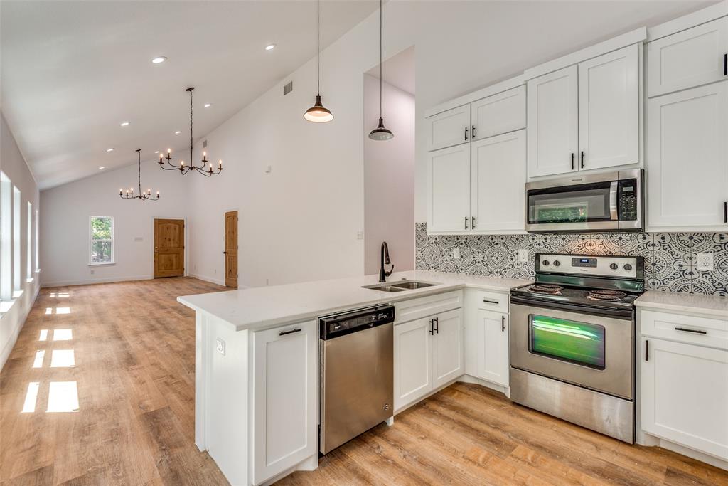1563 Milam Street Fort Worth, TX 76112 - Photo 5 of 12 Kitchen with tasteful backsplash, appliances with stainless steel finishes, white cabinetry, high vaulted ceiling, and a chandelier