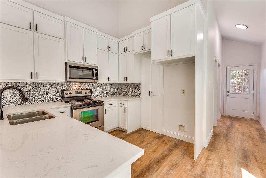 1563 Milam Street Fort Worth, TX 76112 - Photo 6 of 12 Kitchen featuring appliances with stainless steel finishes, decorative backsplash, white cabinetry, light wood-style flooring, and light stone counters