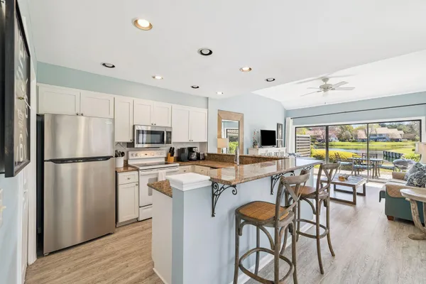 a kitchen with stainless steel appliances a stove a refrigerator a kitchen island a stove and a refrigerator with wooden floor