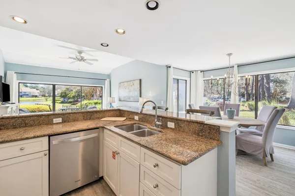 a kitchen with granite countertop a sink and white cabinets with wooden floor