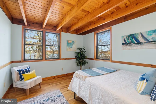 a bedroom with a bed a chair and next to a window