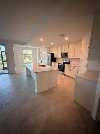a kitchen with stainless steel appliances a refrigerator a sink dishwasher with a dining table and chairs