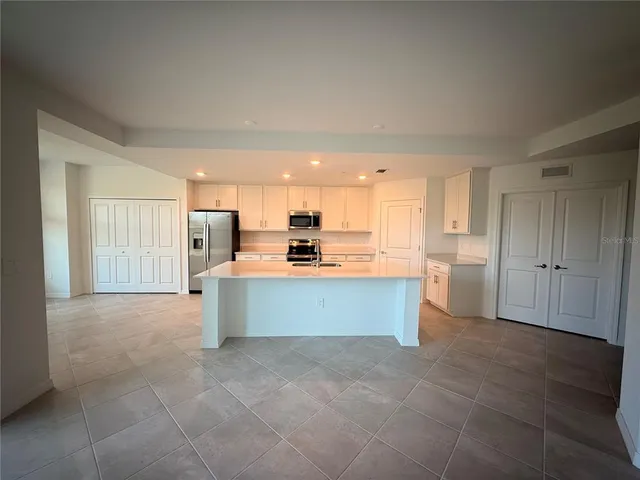 a large kitchen with stainless steel appliances kitchen island granite countertop a refrigerator a sink dishwasher with a dining table and chairs