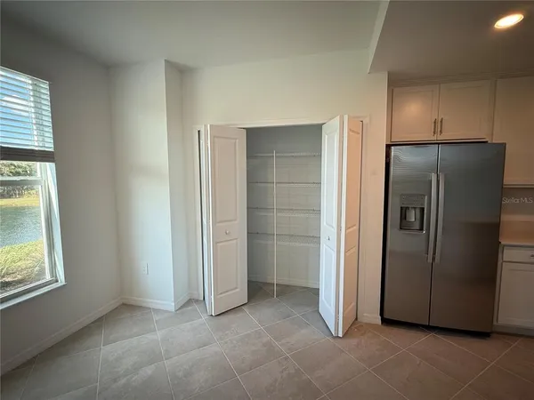 an empty room with windows and refrigerator