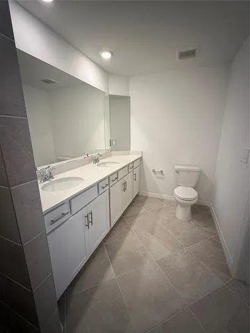a spacious bathroom with a granite countertop toilet and a sink