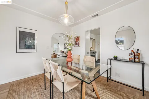 a kitchen with stainless steel appliances a stove a refrigerator and a dining table with wooden floor