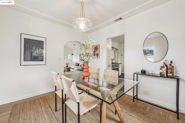 a kitchen with stainless steel appliances a stove a refrigerator and a dining table with wooden floor