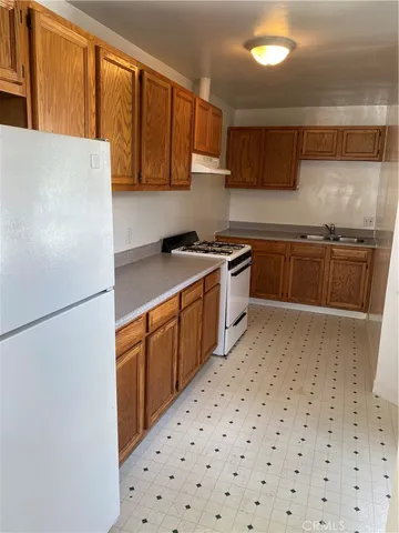 a kitchen with granite countertop a refrigerator a sink and wooden cabinets