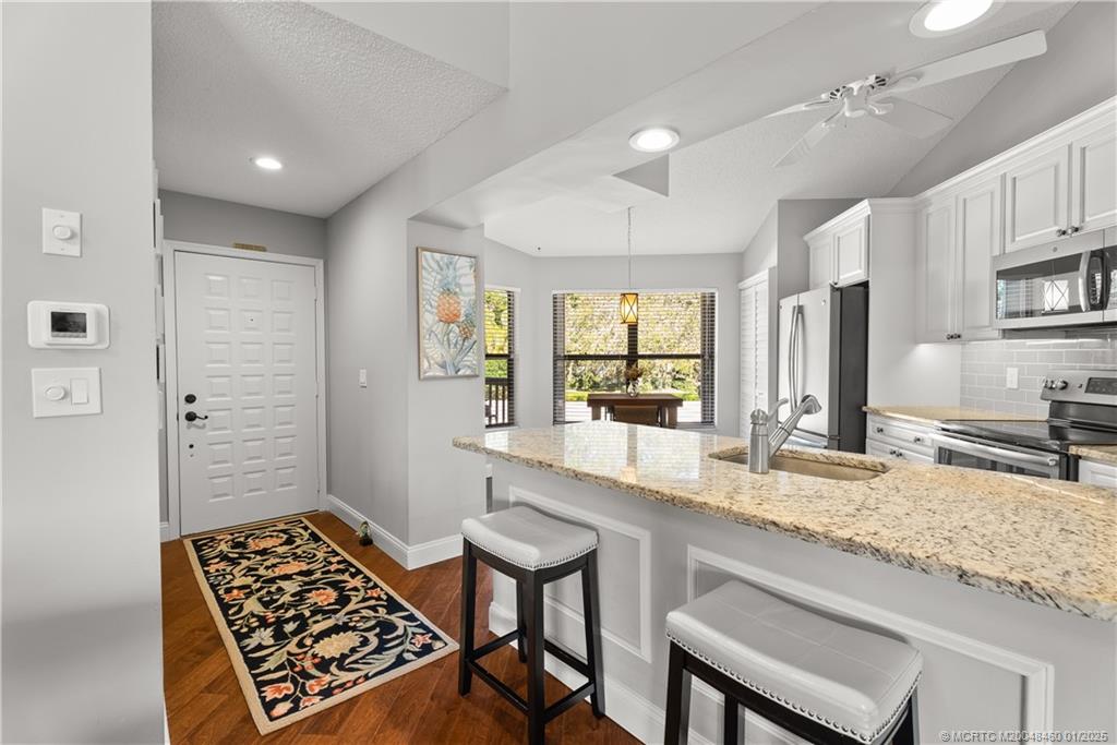 6130 Southeast Martinique Drive, Unit 201 Stuart, FL 34997 - Photo 14 of 36 a kitchen with granite countertop sink cabinets and stainless steel appliances