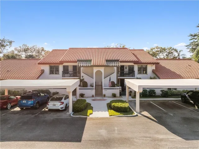 a view of a white house with large windows and a car parked in front of it